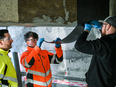 Ekspertene påfører det første laget med karbonfiberstoff på skjærarmeringen.
